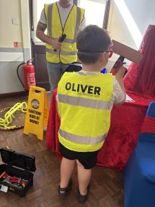 Child in high vis vest holding a brick at a builder themed party