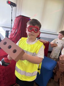 Child in high vis vest holding a brick at a builder themed party
