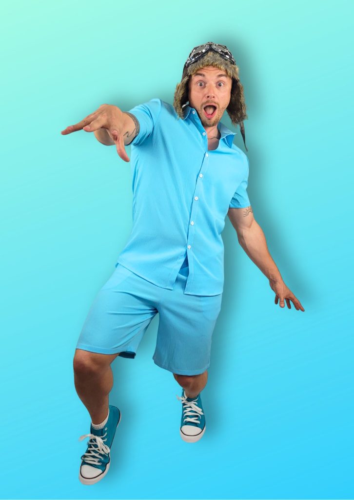 Entertainer dressed as Danny Go. He is wearing a flying hat, blue shorts, shirt and canvas shoes. He is pretending to do the Floor is Lava