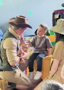 Dino ranger aqt a kids party showing a puppet dino to a child