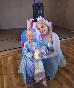 Acrtor dressed as Queen Elsa with a child also dressed as Queen Elsa