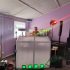 DJ setup with white enclosure, colorful lights, and sound equipment in a room.